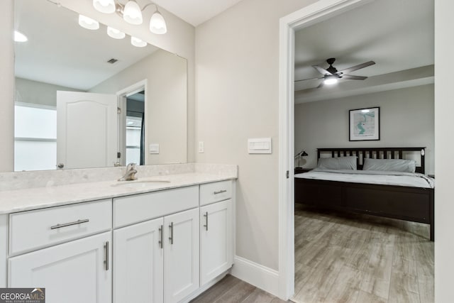 ensuite bathroom with visible vents, ensuite bathroom, ceiling fan, vanity, and wood finished floors