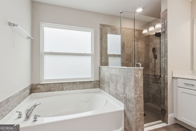 full bathroom featuring a garden tub, a shower stall, and vanity