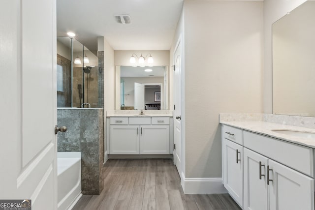 bathroom with visible vents, wood finished floors, a sink, a shower stall, and two vanities