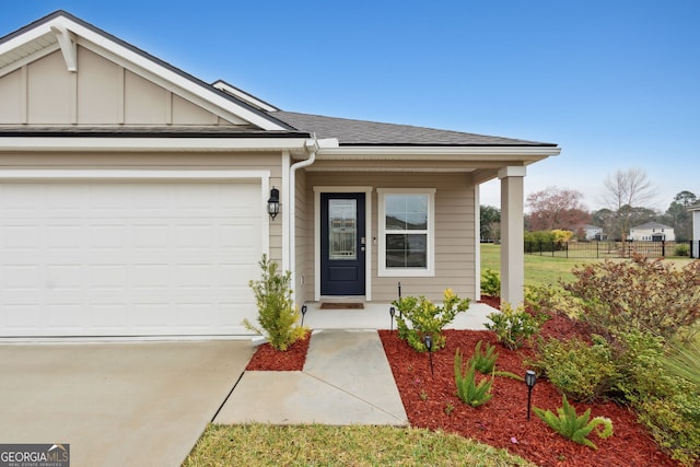 doorway to property featuring an attached garage, a shingled roof, fence, driveway, and board and batten siding