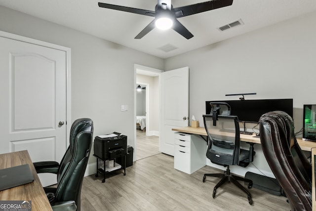 home office with light wood-style floors, visible vents, baseboards, and a ceiling fan