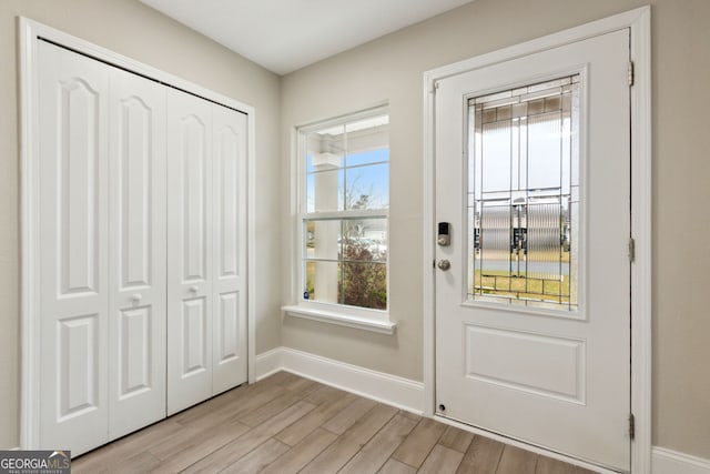 doorway with light wood-type flooring and baseboards