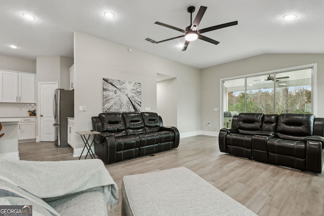 living room with lofted ceiling, light wood-style floors, and a ceiling fan