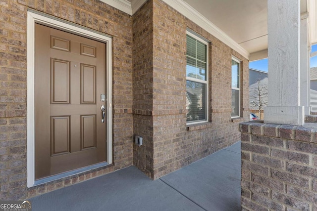 entrance to property featuring covered porch and brick siding