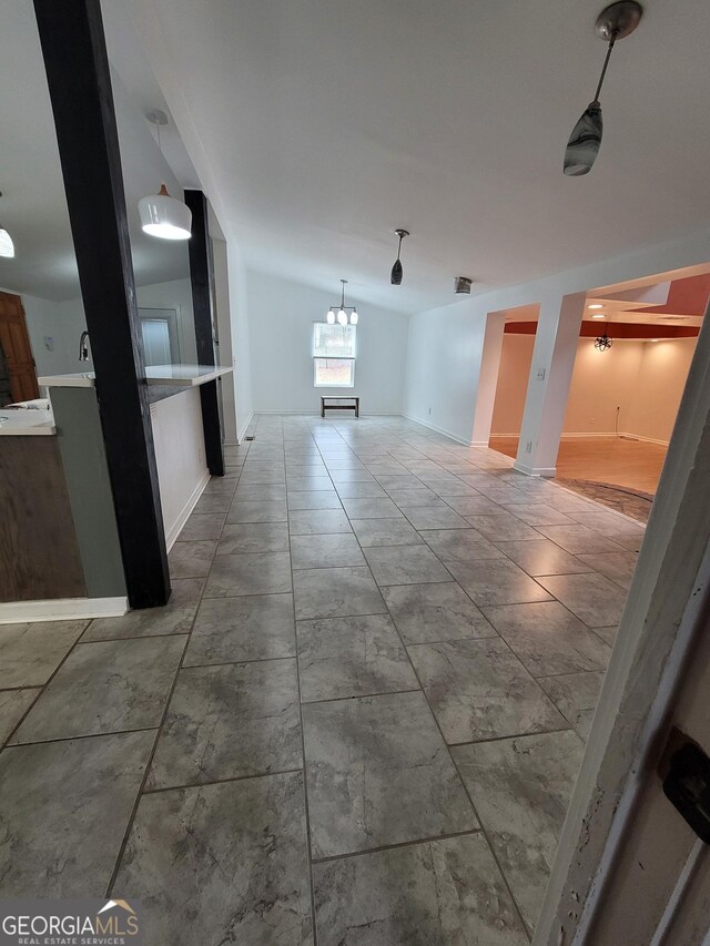 kitchen with lofted ceiling, stainless steel microwave, hanging light fixtures, open floor plan, and a sink