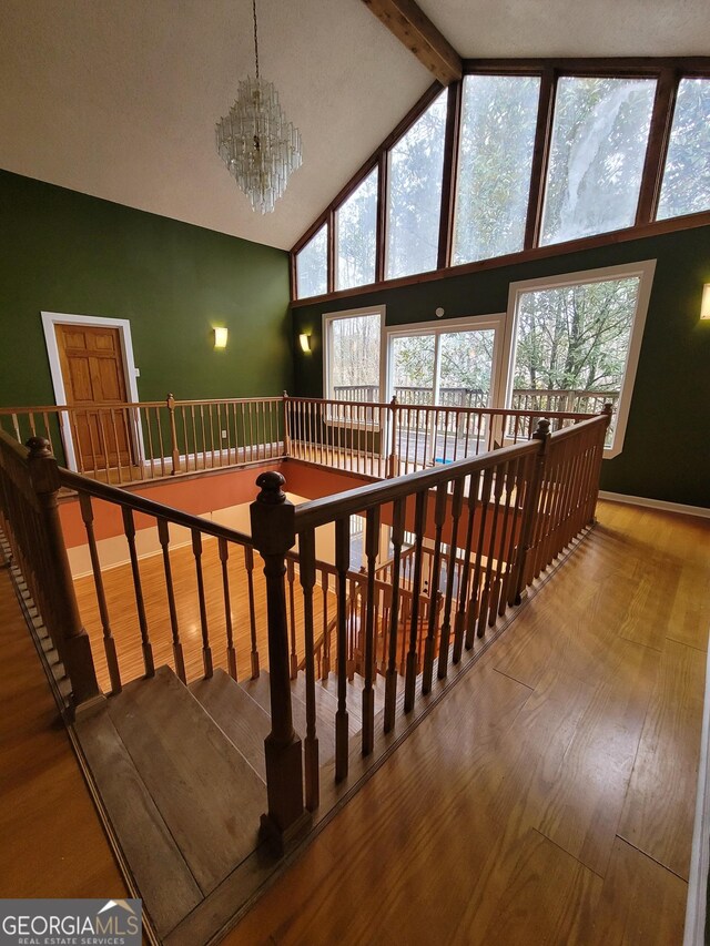 stairs with baseboards, a high ceiling, and wood finished floors