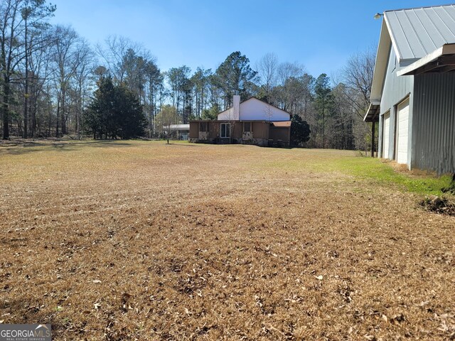 view of property exterior featuring a yard, a chimney, a detached carport, entry steps, and stone siding