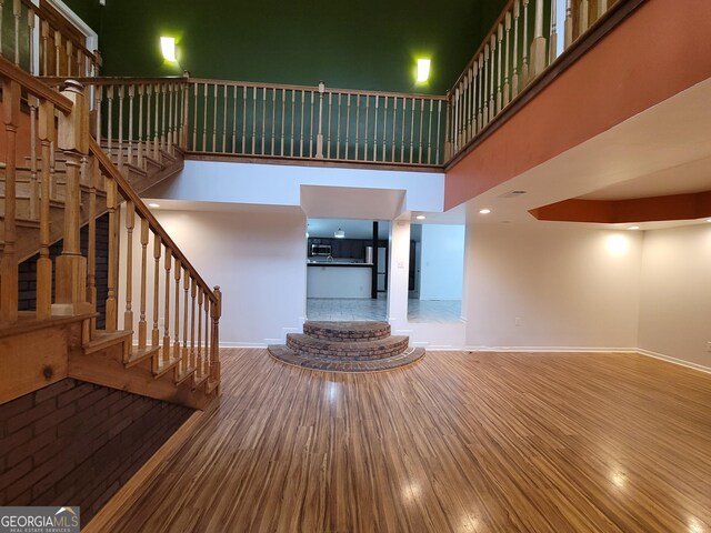 interior space with stairs, a high ceiling, baseboards, and wood finished floors