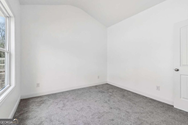 unfurnished room with lofted ceiling, baseboards, and carpet