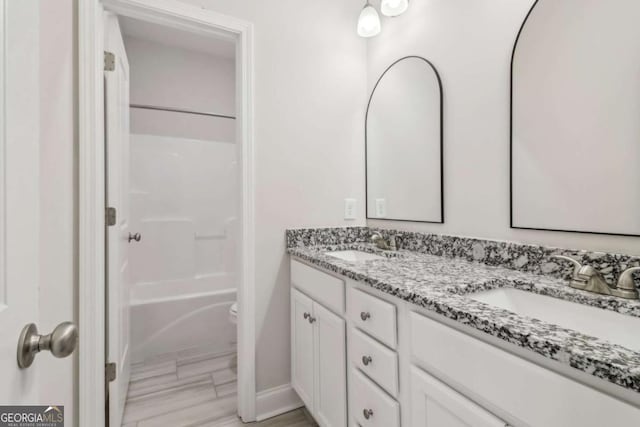 bathroom featuring double vanity, shower / bathing tub combination, a sink, and toilet