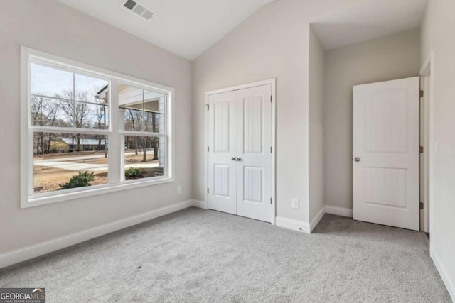 unfurnished bedroom with light carpet, visible vents, baseboards, vaulted ceiling, and a closet