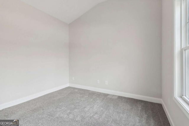 empty room featuring lofted ceiling, carpet flooring, and baseboards