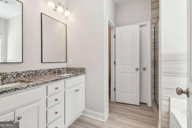 bathroom featuring double vanity, a shower stall, visible vents, and a sink