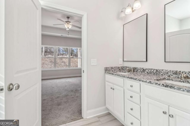 bathroom with double vanity, a sink, a ceiling fan, and baseboards