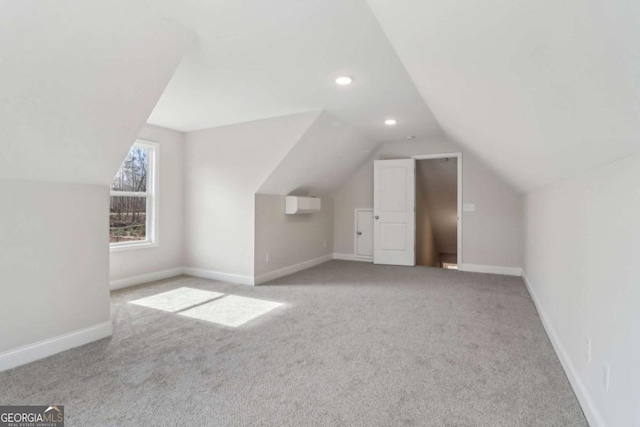 additional living space featuring lofted ceiling, an AC wall unit, light carpet, and baseboards