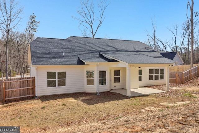 rear view of house with a patio area, a fenced backyard, and roof with shingles