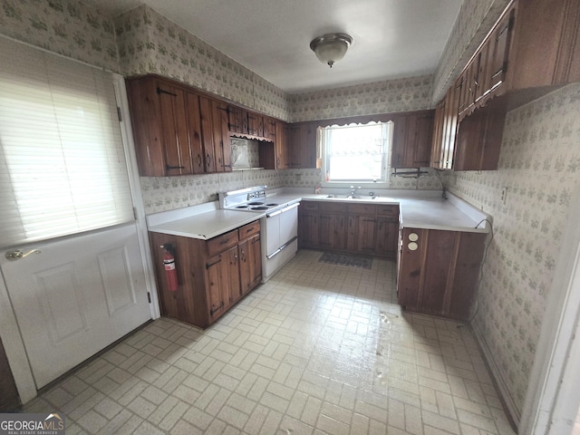 kitchen featuring electric stove, light countertops, a sink, and wallpapered walls