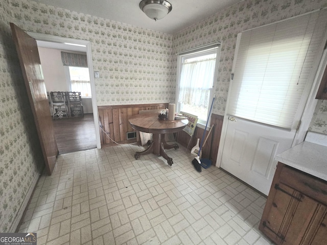 dining space featuring brick patterned floor, wainscoting, visible vents, and wallpapered walls