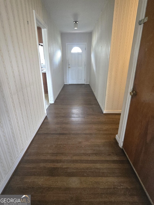 entryway featuring dark wood-style flooring, baseboards, and wallpapered walls