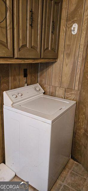 laundry room with washer / clothes dryer, cabinet space, and wooden walls