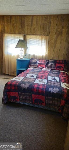 carpeted bedroom with wood walls