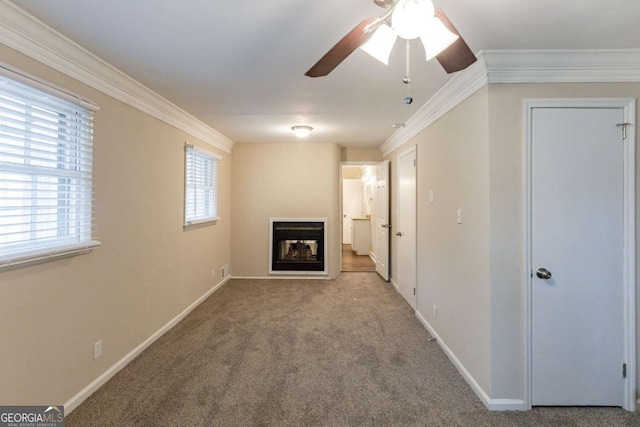 unfurnished living room with carpet floors, plenty of natural light, a glass covered fireplace, and crown molding