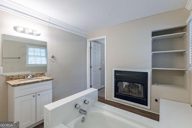 full bath featuring a garden tub, a fireplace, and vanity