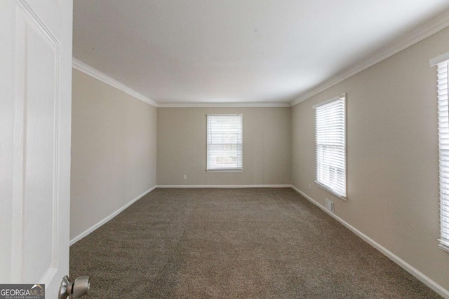 empty room featuring a healthy amount of sunlight, baseboards, dark colored carpet, and crown molding