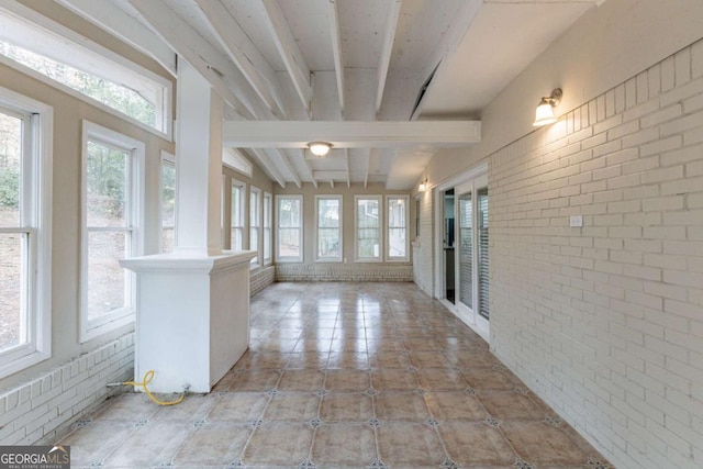 unfurnished sunroom featuring beam ceiling