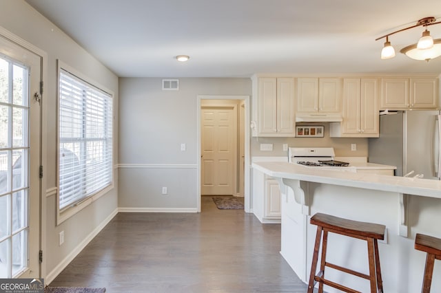 kitchen with range, a breakfast bar, freestanding refrigerator, light countertops, and under cabinet range hood