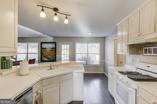 kitchen with a sink, light countertops, white gas stove, under cabinet range hood, and stainless steel dishwasher