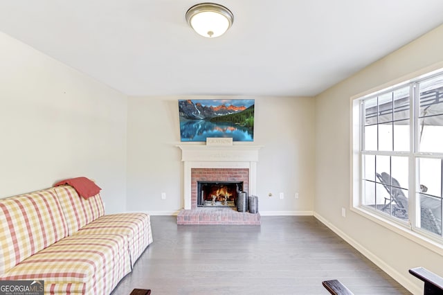 living area with a brick fireplace, baseboards, and wood finished floors