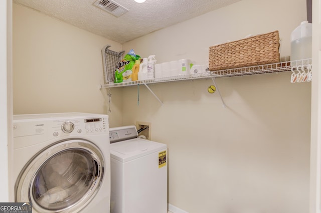 clothes washing area with washing machine and dryer, laundry area, visible vents, and a textured ceiling