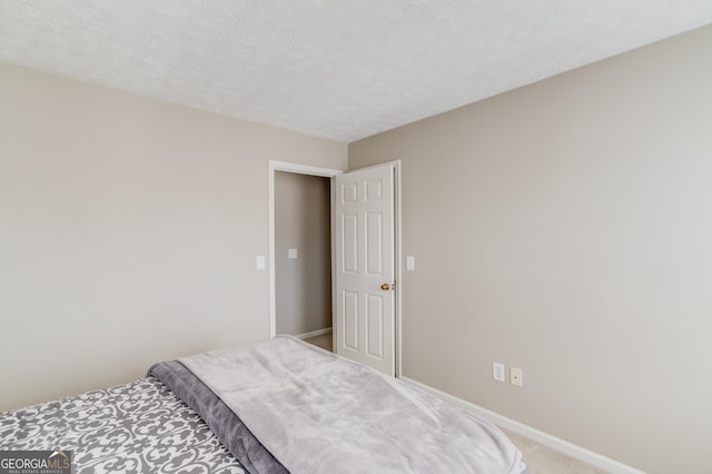 bedroom featuring a textured ceiling, baseboards, and light colored carpet