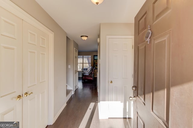 corridor with dark wood-style flooring and baseboards