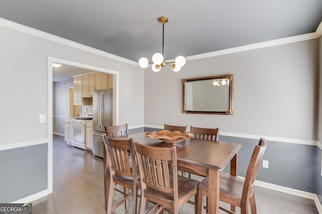 dining room with an inviting chandelier, crown molding, baseboards, and wood finished floors