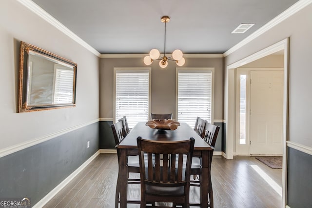 dining space with ornamental molding, visible vents, dark wood finished floors, and a notable chandelier