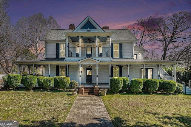 victorian home featuring ceiling fan, a porch, a front lawn, and a balcony