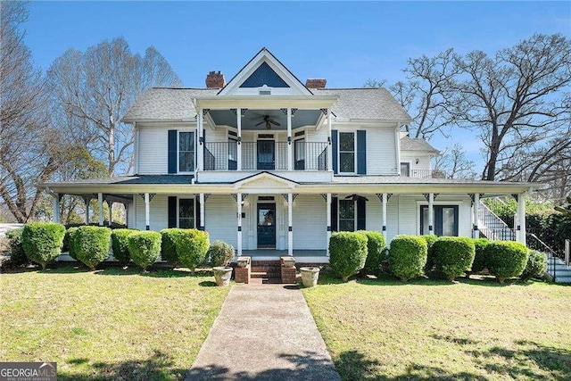 view of front of house featuring a porch, a front yard, a chimney, and a ceiling fan