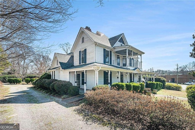 view of front of property with driveway, a porch, roof with shingles, and a balcony