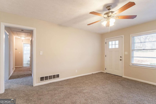 interior space with attic access, a textured ceiling, visible vents, and carpet flooring