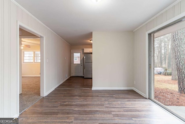 empty room featuring baseboards, ornamental molding, and dark wood-style flooring