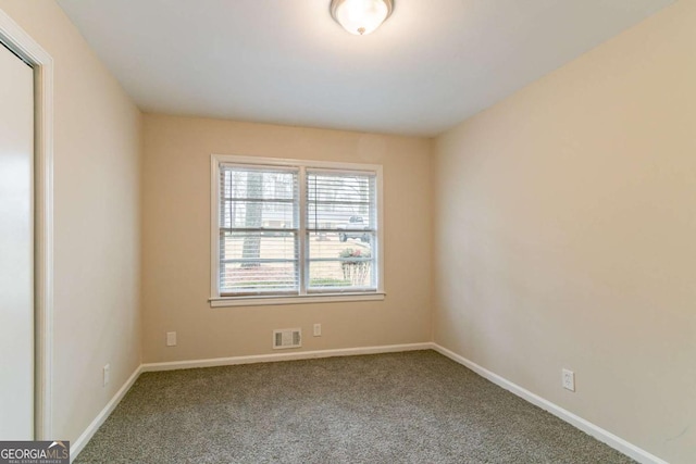 empty room with carpet, visible vents, and baseboards