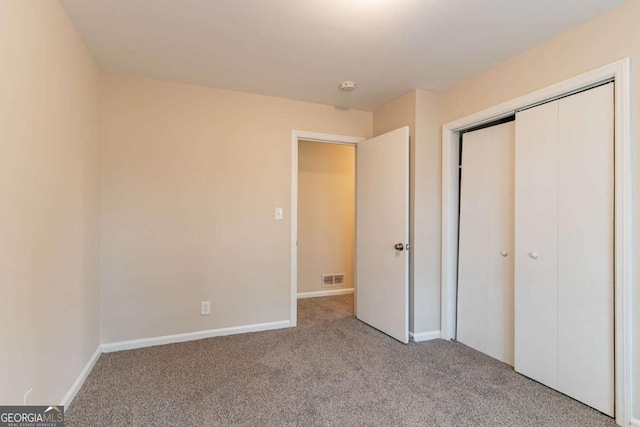 unfurnished bedroom with carpet, a closet, visible vents, and baseboards