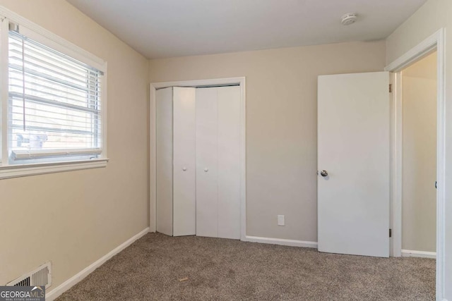 unfurnished bedroom with a closet, carpet, visible vents, and baseboards