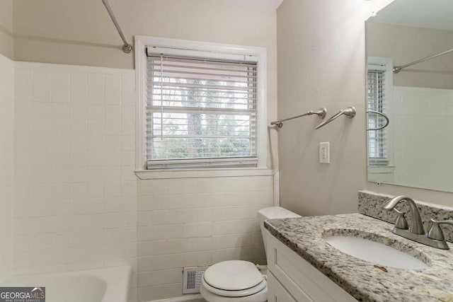 bathroom featuring shower / tub combination, toilet, visible vents, vanity, and tile walls