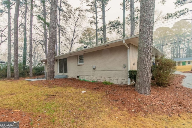 view of side of home with a lawn and brick siding