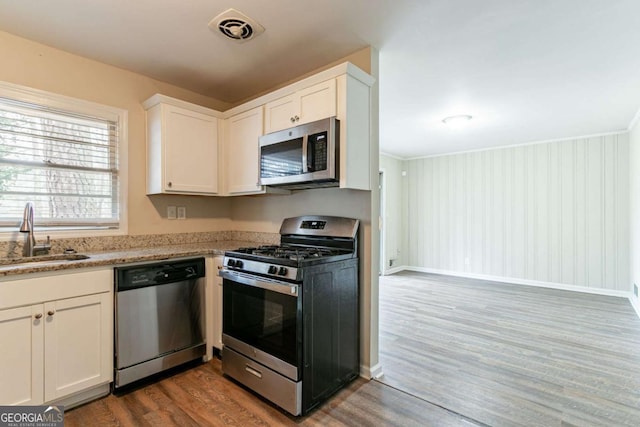 kitchen featuring appliances with stainless steel finishes, white cabinetry, a sink, and visible vents