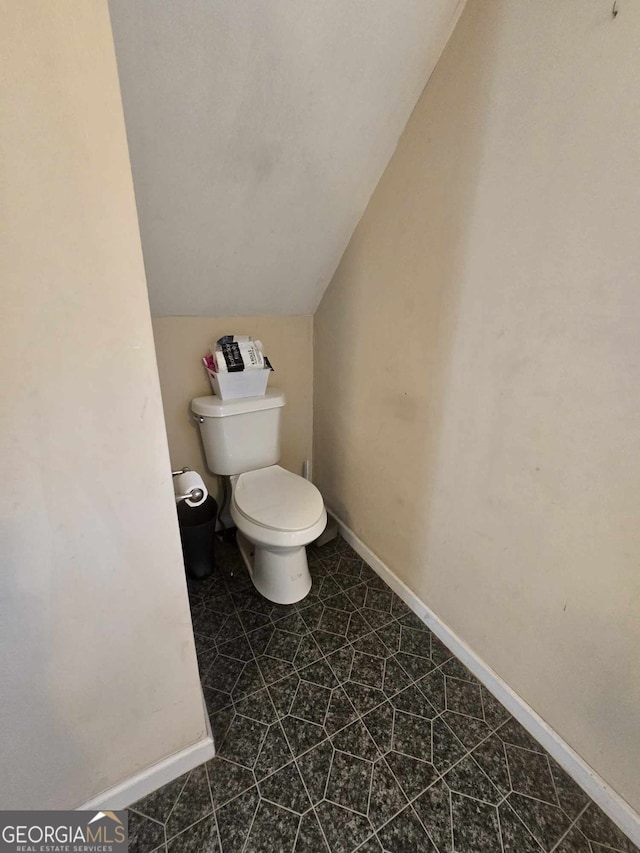 half bath with vaulted ceiling, toilet, and baseboards