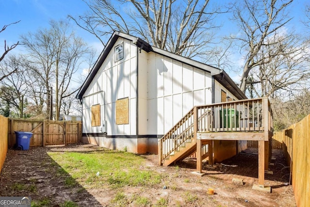 rear view of house featuring stairway, board and batten siding, a fenced backyard, and a wooden deck